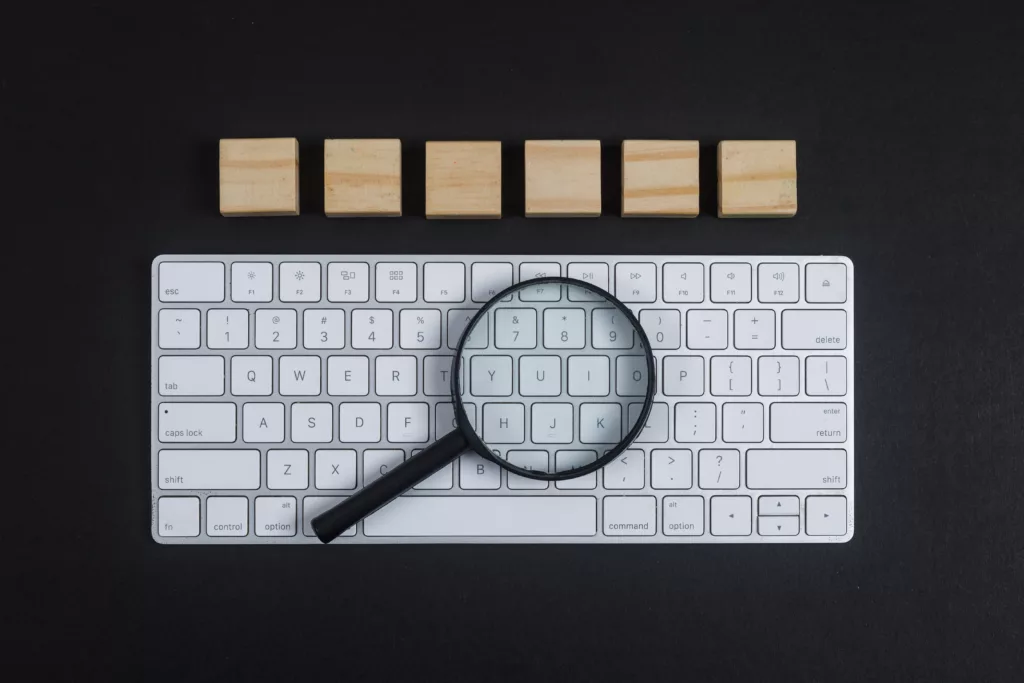 Conceptual of research with keyboard magnifier wooden cubes on black desk background flat lay horizontal image