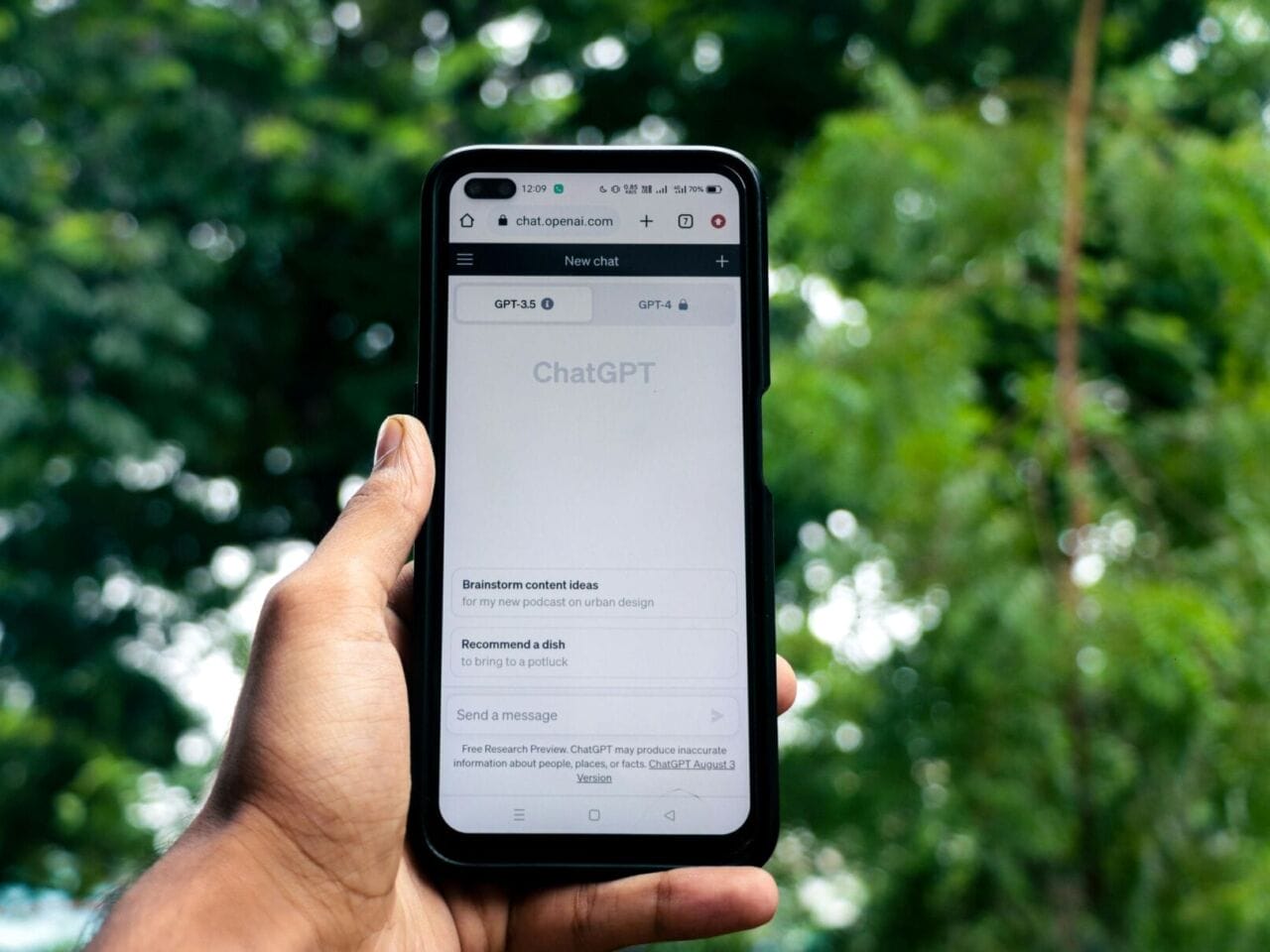 A hand holds a phone with the "ChatGPT" site on the screen.